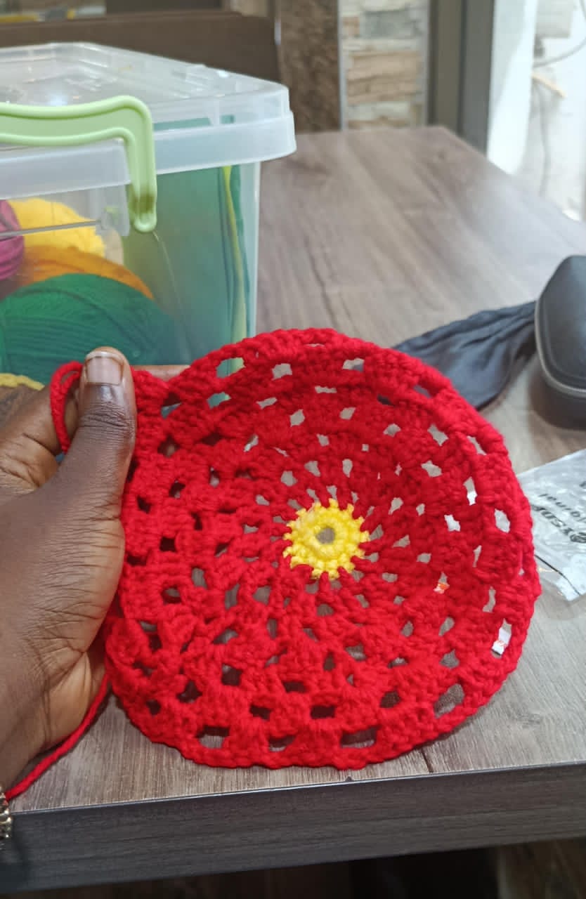 A completed red circular crochet doily with a yellow centre