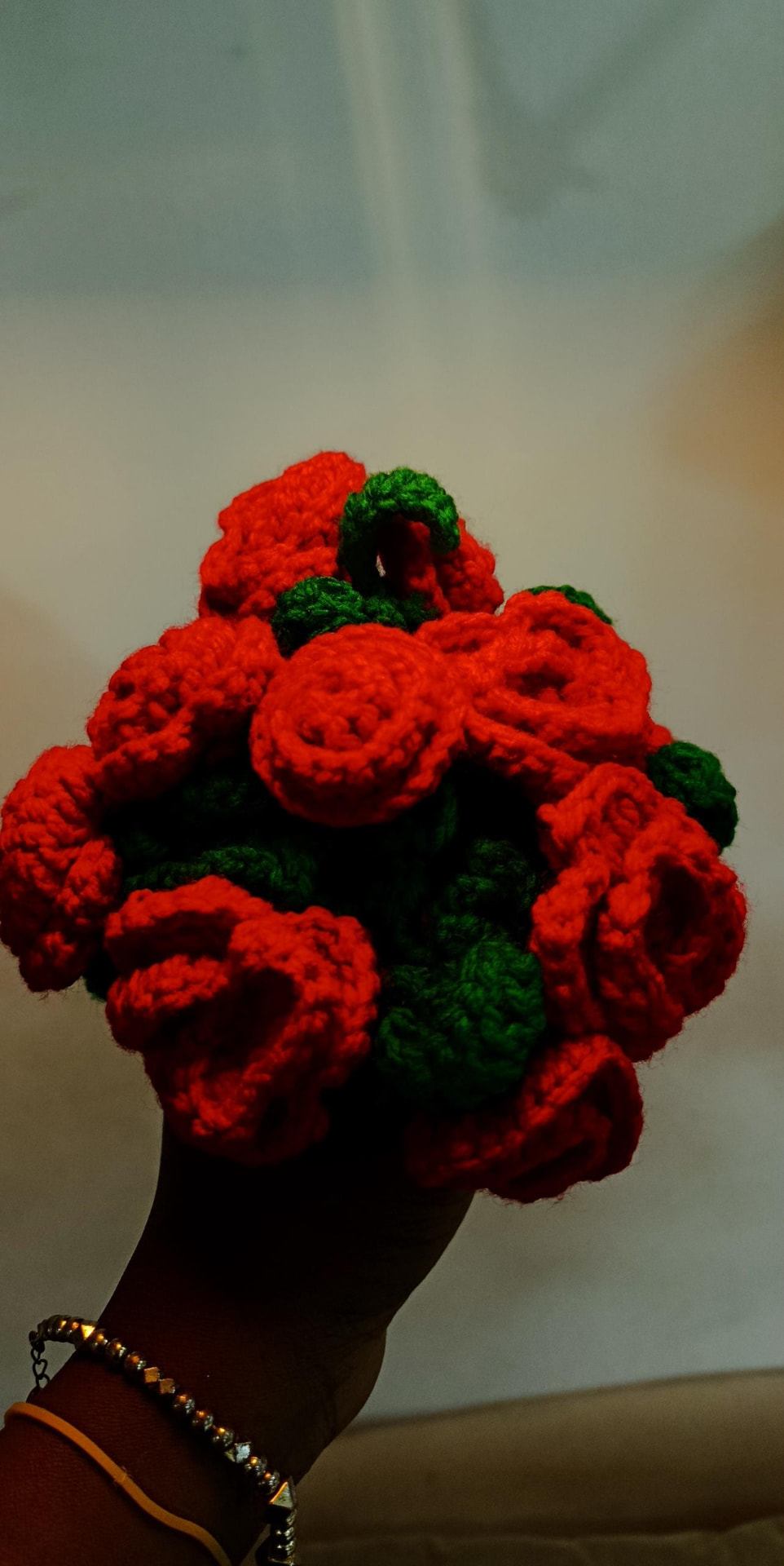 A handful of red crochet roses held up to the light