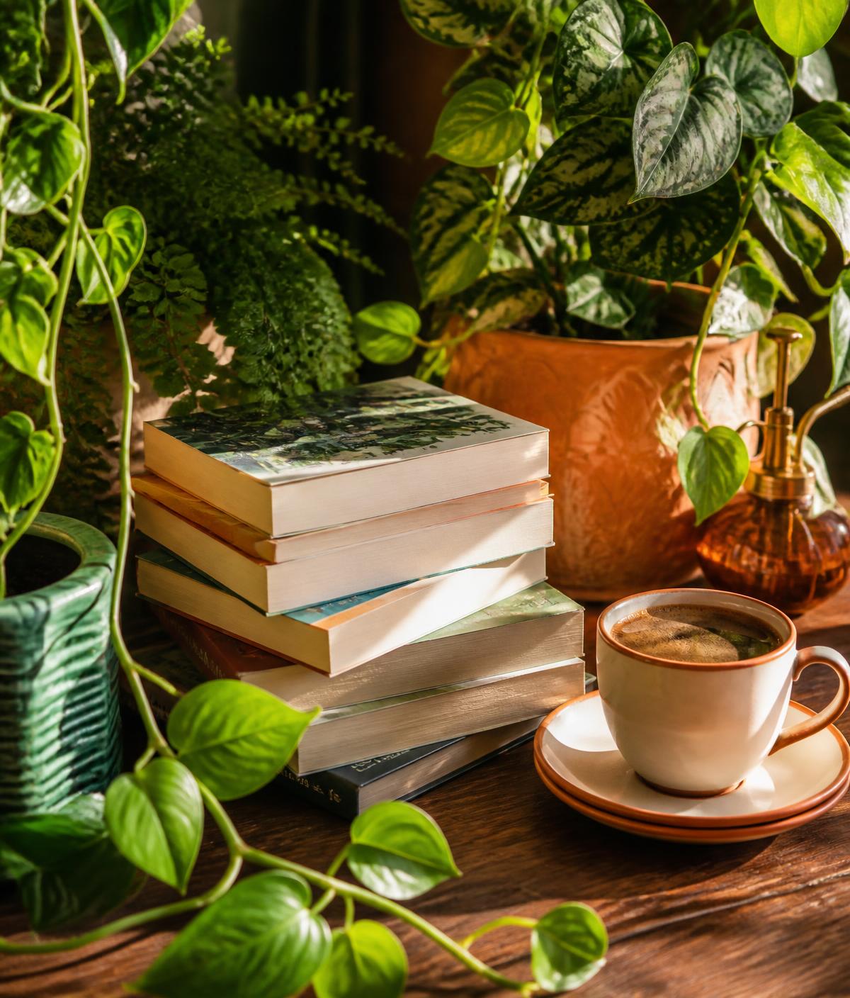 A stack of well-read paperbacks beside a cup of coffee